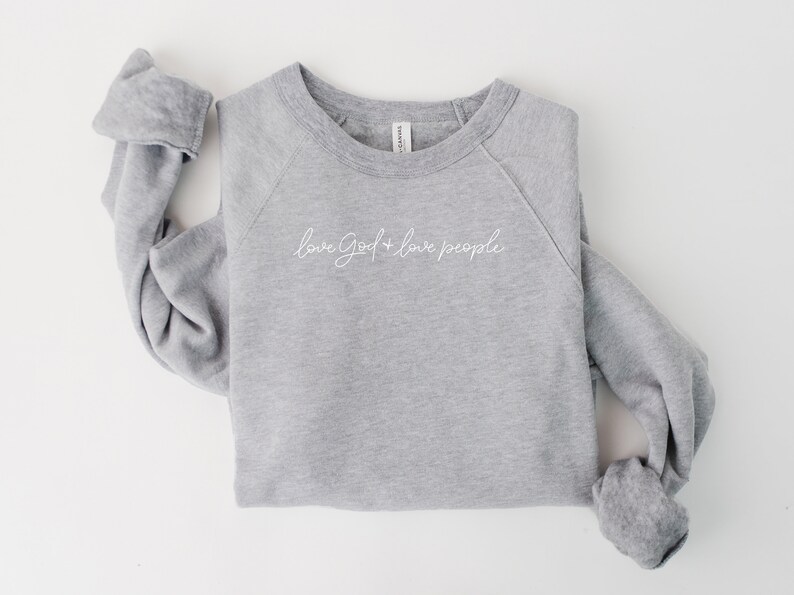 Peut inclure: Un sweat-shirt gris chin&eacute; avec le texte "love God + love people" en lettres blanches en cursive.