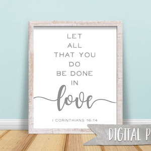 May include: A white framed print with a gray text quote that reads "Let all that you do be done in love" with the scripture reference "1 Corinthians 16:14" below the quote. The print has a distressed white frame and a gray background.