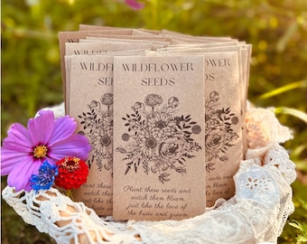 May include: A basket filled with small brown paper packets of wildflower seeds. The packets have a black and white illustration of wildflowers and the text "Wildflower Seeds". The text on the front of the packet reads "Plant these seeds and watch them bloom, just like the love of the bride and groom."