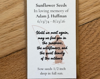 May include: A rectangular paper packet of sunflower seeds featuring the text: Sunflower Seeds, In loving memory of Adam J. Huffman, 6/13/74 - 8/23/26, Until we meet again, may we find you in the sunshine, the wildflowers, and the quiet beauty of the outdoors. Sow seeds 1/2 inch deep in full sun. A light brown silhouette of a person fishing is printed in the center.