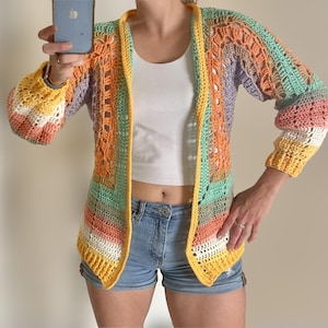 May include: A colourful crochet cardigan with a rainbow stripe pattern. The cardigan has a loose fit and a V-neck.