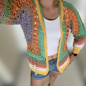 K&ouml;nnte beinhalten: Eine mehrfarbige H&auml;keljacke mit gelbem Besatz. Die Jacke ist vorne offen und hat eine lockere Passform.