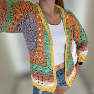 K&ouml;nnte beinhalten: Eine mehrfarbige H&auml;keljacke mit gelbem Besatz. Die Jacke ist vorne offen und hat eine lockere Passform.