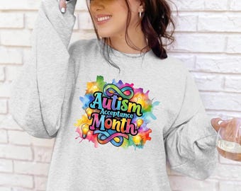 May include: A grey sweatshirt with a colourful graphic design that says "Autism Acceptance Month" with light bulbs and a rainbow infinity symbol.