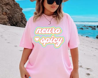 May include: A pink t-shirt with the text "neuro spicy" in rainbow colors with a heart symbol before the word "spicy".