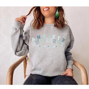 May include: Gray sweatshirt with the text "Anxiety University Honors Program" in a rainbow arc design.