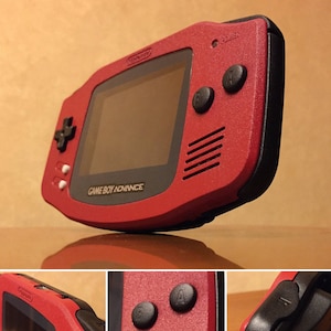 May include: A red Game Boy Advance handheld video game console with a black screen and buttons. The console has a textured surface and the text "GAME BOY ADVANCE" is printed on the front.