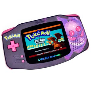 May include: A custom Game Boy Advance handheld console featuring a Pokémon FireRed game. The console has a purple body with pink accents and a Gengar design. The screen displays the game's title screen.
