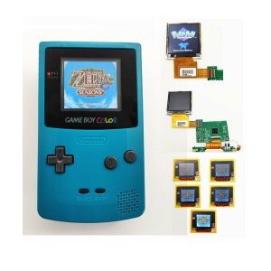 May include: A teal Game Boy Color handheld gaming console with a game cartridge inserted. The game is The Legend of Zelda: Oracle of Seasons. The console is next to a circuit board and several game cartridges.