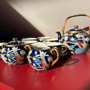 Può includere: Un set di tre ciotole impilabili in ceramica nei toni del blu, verde e bianco. Le ciotole presentano una smaltatura maculata e un design semplice e moderno. La ciotola più grande ha un diametro di circa 15 cm.