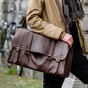 The leather bag is equipped with two short handles for carrying, and a long strap to carry on the shoulder.