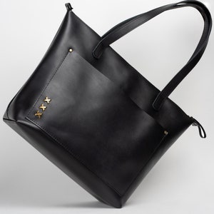 The front of the black leather bag is designed with a pocket that can hold many necessary items