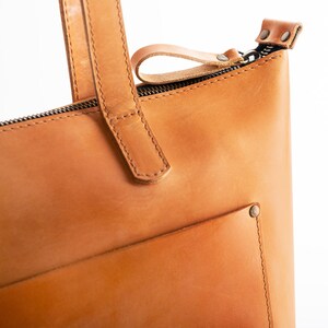 A durable full-grain leather tote bag with a matte honey finish, designed to last.a large light cognac purse with a spacious front pocket, made from genuine thick honey-colored leather.