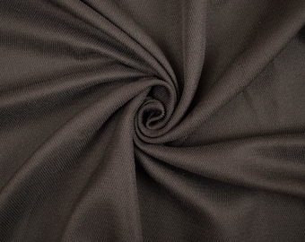 May include: Close-up of a dark brown fabric with a textured, woven pattern. The fabric is folded and draped, creating a soft, flowing effect.
