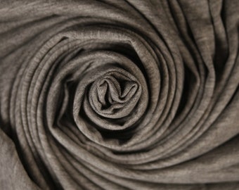 Könnte beinhalten: Nahaufnahme eines grauen Stoffes, der zu einer spiralförmigen Form gerollt ist, die einer Rose ähnelt.