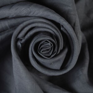 May include: A close-up of a dark gray fabric folded into a spiral shape, resembling a rose.