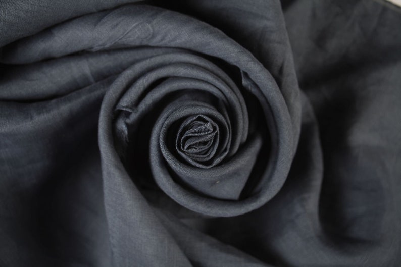 May include: A close-up of a dark gray fabric folded into a spiral shape, resembling a rose.