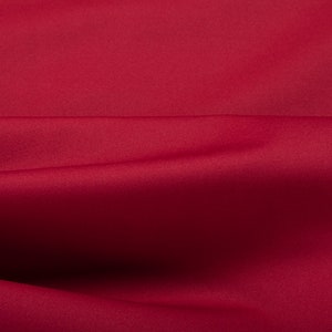 Pode incluir: Close-up de um tecido liso vermelho escuro com uma dobra sutil no centro.