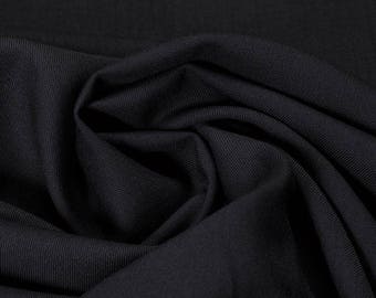 Puede incluir: Primer plano de una tela negra con una superficie lisa y texturizada. La tela está doblada y drapeada, mostrando su suavidad y flexibilidad.