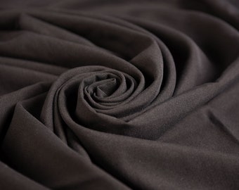 Peut inclure: Gros plan sur un tissu gris foncé drapé et plié en forme de rose.
