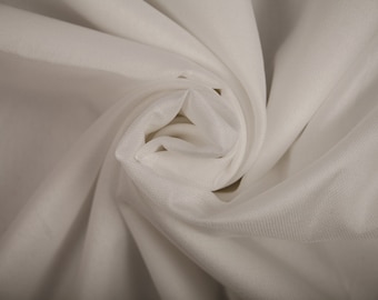 May include: White fabric with a soft, smooth texture, draped and folded to create a swirling pattern.
