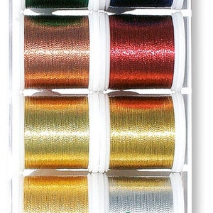 May include: A set of eight spools of Madeira embroidery thread in various metallic colours, including green, blue, copper, red, gold, and silver. The spools are arranged in a clear plastic case with the Madeira brand name visible.
