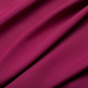 Può includere: Primo piano di un tessuto liscio rosa intenso con una texture sottile. Il tessuto è piegato e drappeggiato, creando linee morbide e fluide.