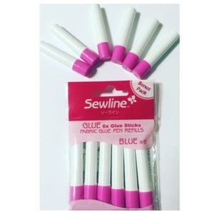 以下が含まれることがあります： Sewline製の青い布用接着剤ペンリフィル6本入りパック。パッケージはピンクと白で、"Sewline"と"Glue 6x Glue Sticks Fabric Glue Pen Refills Blue x 6"の文字が書かれています。
