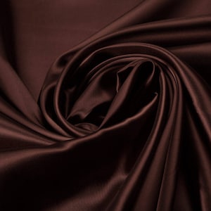 Puede incluir: Primer plano de una tela de satén marrón oscuro, mostrando la textura suave y fluida y el brillo sutil del material.