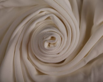 May include: A close-up of a white fabric rolled into a spiral shape, creating a soft and delicate texture.