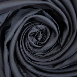 May include: Close-up of a dark gray fabric swirled into a rose shape.