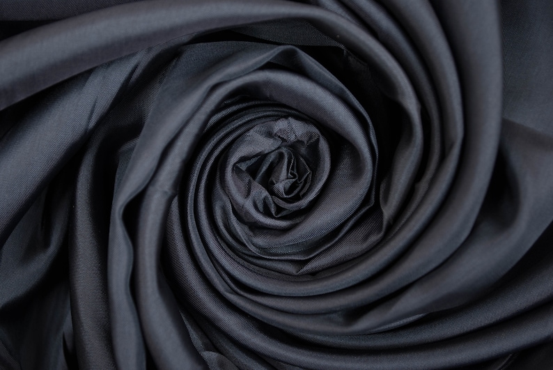 May include: Close-up of a dark gray fabric swirled into a rose shape.