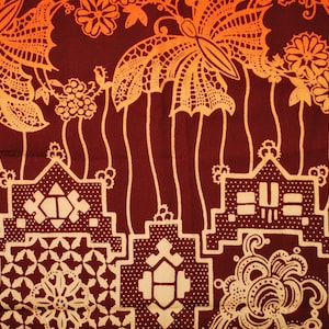 Könnte beinhalten: Ein roter und orangefarbener Stoff mit einem sich wiederholenden Muster aus stilisierten Schmetterlingen, Blumen und geometrischen Formen. Der Stoff hat einen Vintage-Charakter und ist perfekt für Bastelarbeiten.
