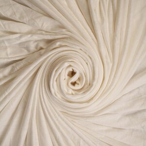 Peut inclure: Un gros plan sur un tissu blanc enroulé en spirale. Le tissu est doux et lisse, créant un motif délicat et élégant.