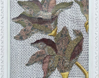 May include: A framed artwork featuring two stylised flowers made of beads and sequins. The flowers are in shades of pink, brown, and gold, and are set against a white background with a grid pattern.