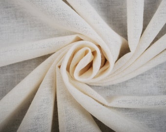 May include: A close-up of a white cotton fabric, folded and twisted into a spiral shape. The fabric is soft and textured, with a subtle sheen.