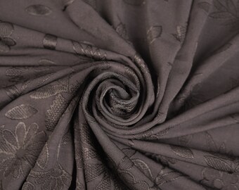 May include: Close-up of a dark gray fabric with a subtle embossed floral pattern. The fabric is folded and twisted, creating a soft, textured look.