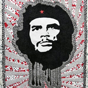 May include: Black and white portrait of a man wearing a red star on his hat. The background is a red, white and black geometric pattern.