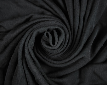 May include: A close-up of a black fabric swirled into a spiral shape. The fabric has a soft, textured surface.