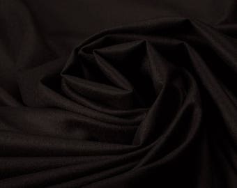 Puede incluir: Tela negra con una superficie lisa y ligeramente texturizada. La tela está doblada y drapeada, creando curvas y pliegues suaves.