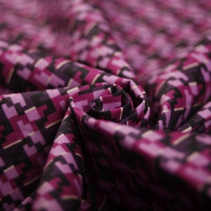 Könnte beinhalten: Nahaufnahme eines violetten und schwarzen Stoffes mit geometrischem Muster. Der Stoff ist gefaltet und texturiert.