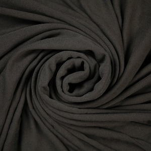May include: Close-up of a dark gray fabric with a soft, textured surface. The fabric is folded and twisted, creating a swirling pattern.