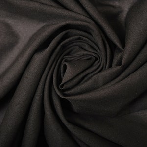 May include: Close-up of a black fabric with a soft, smooth texture. The fabric is folded and twisted into a spiral shape, creating a dramatic and elegant look.