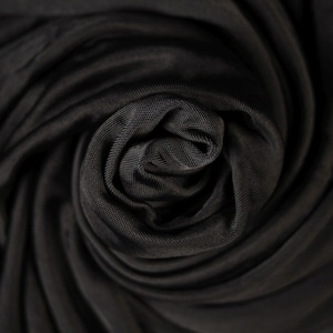 May include: Close-up of black fabric with a smooth, silky texture. The fabric is gathered and twisted, creating a swirling pattern.