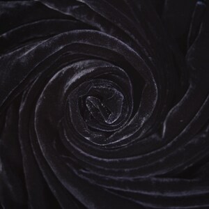 May include: Close-up of a dark gray velvet fabric swirled into a spiral shape.