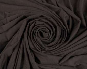 May include: Close-up of a dark brown fabric swirled into a spiral shape. The fabric is soft and smooth, with a subtle sheen.