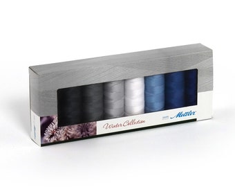 May include: A box of Mettler sewing thread in a winter collection color palette. The box contains eight spools of thread in shades of gray, white, and blue. The box has a wood-grain pattern and a clear window showing the thread spools.