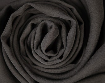 Può includere: Primo piano di tessuto nero piegato a spirale, che mostra la trama e il drappeggio del materiale.