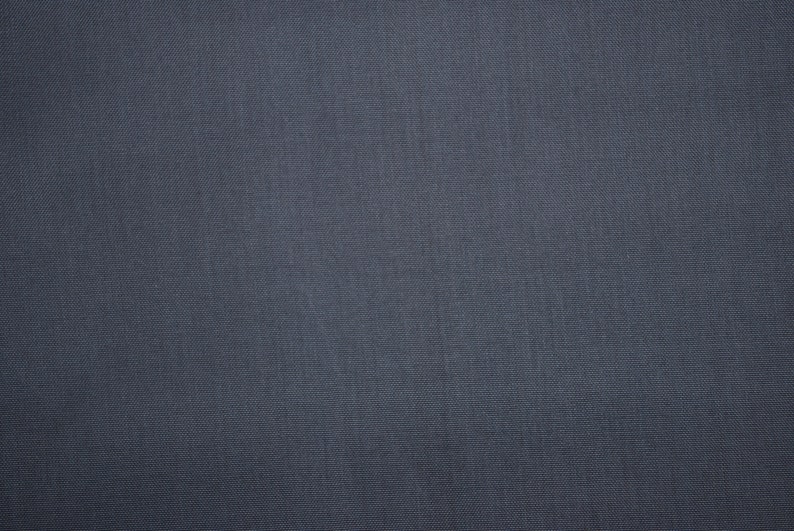 May include: A close-up of a dark gray fabric with a subtle texture. The fabric has a smooth, even surface with a slight sheen.