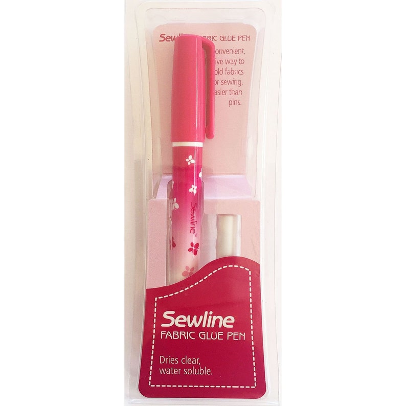 May include: A pink fabric glue pen with a floral design. The pen is packaged in a clear plastic container with a pink and white label that reads "Sewline Fabric Glue Pen" and "Dries clear, water soluble."